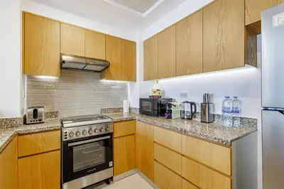 a kitchen with wooden cabinets and a stove top oven at Stunning Skyline Views and Prime Walkable Location in Dubai