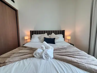 a bedroom with a large white bed with towels on it at Modern & Cozy 1BR Apartment with Full Comfort in Dubai