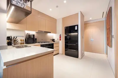 a kitchen with wooden cabinets and a black refrigerator at 4BR Luxury Hotel Amenities Dubai Mall Access in Dubai