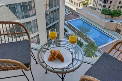 a table with two glasses of orange juice and croissants on a balcony at Luxury 1BHK Burj Khalifa View Short Walk Dubai Mall in Dubai