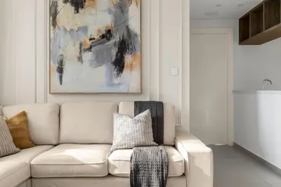 a living room with a white couch and a painting at Stylish 2 bedroom with Burj Khalifa View, connected to Dubai Mall in Dubai