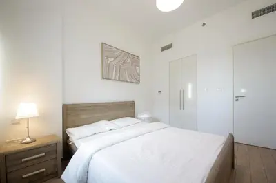 a white bedroom with a large bed and a lamp at Silk Valley - Luxury 2B steps from Metro station in Dubai