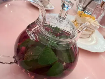 a glass jug filled with green leaves on a table at Diligence Barsha Apartment in Dubai
