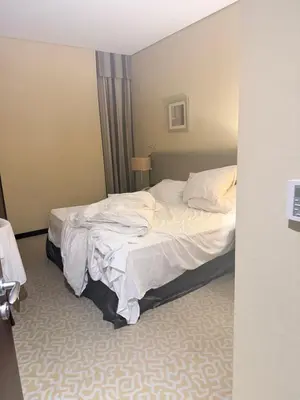 a hotel room with a bed with white sheets at Diligence Barsha Apartment in Dubai
