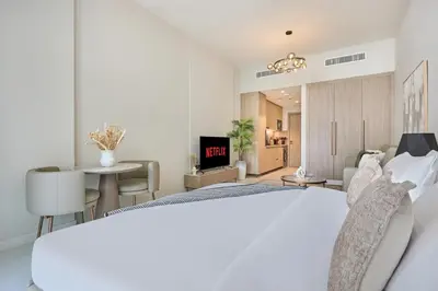 a bedroom with a white bed and a living room at Pool View Studio Near to circle mall - Icon casa Living in Dubai