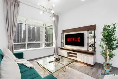a living room with a couch and a tv at Stunning 1BR l JLTl Steps to Metro! in Dubai