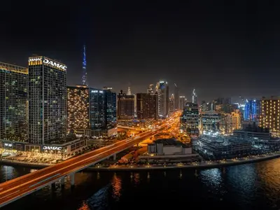a city skyline at night with a bridge over the water at Luxurious 3BR Stunning Canal & Burj Khalifa View in Dubai