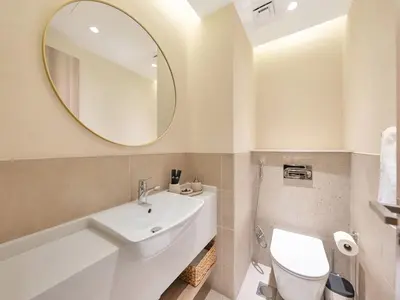 a white bathroom with a sink and a mirror at Luxurious 3BR Stunning Canal & Burj Khalifa View in Dubai