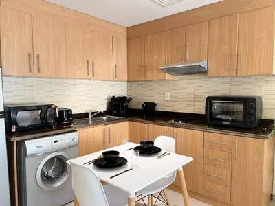a kitchen with a white table and a microwave at ASHRI HH | Spacious Studio in Arjan in Dubai