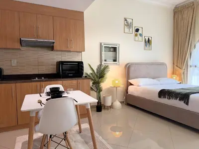 a bedroom with a bed and a table and a kitchen at ASHRI HH | Spacious Studio in Arjan in Dubai