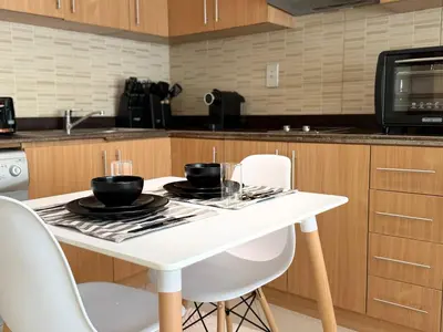 a kitchen with a white table with chairs and a microwave at ASHRI HH | Spacious Studio in Arjan in Dubai