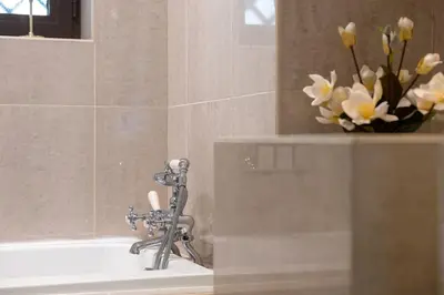 a bath tub with a faucet and a vase of flowers at Authentic Arabic Lux Stay -Seconds to Burj Khalifa in Dubai