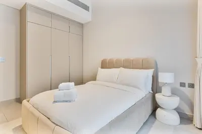 a white bedroom with a large bed with white sheets at MAG City Private Villa, 3BR with Pool, Garden & BBQ in Dubai