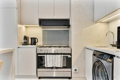 a kitchen with a stove and a washing machine at MAG City Private Villa, 3BR with Pool, Garden & BBQ in Dubai