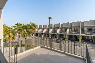 an apartment building with a fence and palm trees at MAG City Private Villa, 3BR with Pool, Garden & BBQ in Dubai