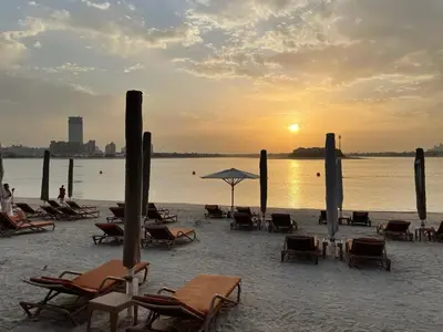 a group of chairs and umbrellas on a beach at FIRST CLASS 1BR Serene Sea View Royal Amwaj in Dubai