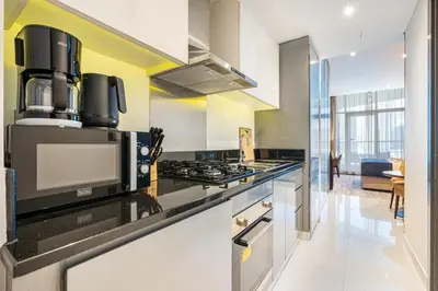 a kitchen with a stove top oven next to a counter at Sleek Home in Business Bay with Panoramic Views in Dubai