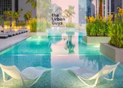 a swimming pool with two white chairs in a building at Livo in Dubai