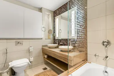 a bathroom with two sinks and a toilet and a mirror at VayK - Luxurious 3BR in Business Bay with Burj Khalifa View in Dubai