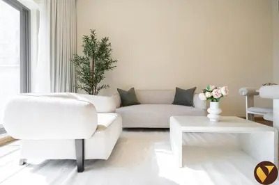 a white living room with a couch and a table at Vogue JVC Jeewar Tower Near Circle Mall, One Bedroom Apartment with Balcony and City View, Access to all Amenities in Dubai