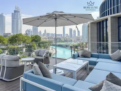 a patio with blue couches and a table and an umbrella at Address Residences Dubai Opera 3-bed Full Burj & Fountain View, Downtown Dubai in Dubai
