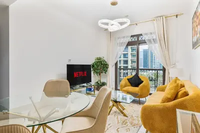 a living room with a glass table and yellow chairs at Charming Oasis Near Dubai Mall & Burj Khalifa in Dubai