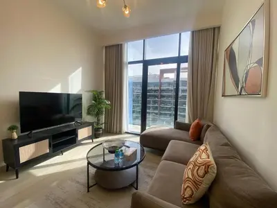 a living room with a couch and a large window at Large 1 Bedroom Apartment in Azizi Riviera 15 in Dubai
