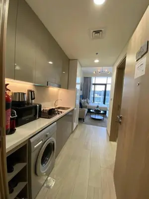 a kitchen with a washing machine and a living room at Modern Studio with Balcony - Pool View in Dubai