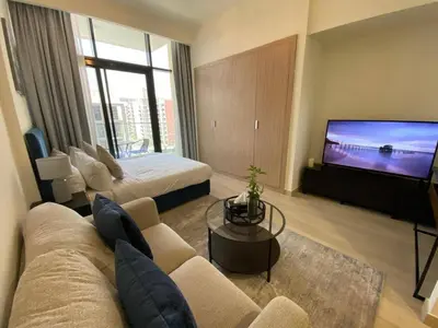 a living room with a couch and a flat screen tv at Modern Studio with Balcony - Pool View in Dubai
