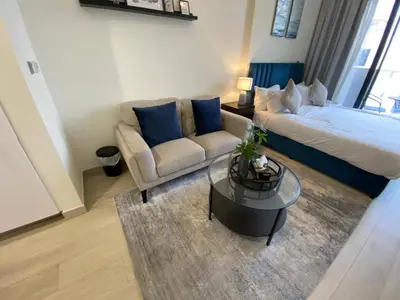 a living room with a bed and a couch and a table at Modern Studio with Balcony - Pool View in Dubai