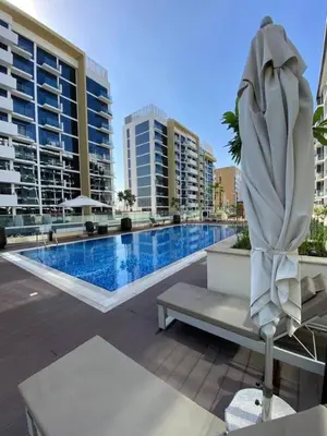 a large swimming pool with a white umbrella and a chair at Bright Studio - Azizi Riviera 35 - Fully Furnished in Dubai