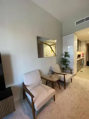 a living room with a chair and a table at Bright Studio - Azizi Riviera 35 - Fully Furnished in Dubai