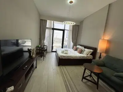 a room with a bed and a couch and a tv at Stylish Studio Retreat, Meydan Area and Pool Access in Dubai