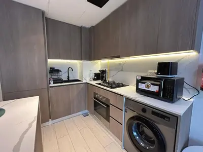 a kitchen with a washing machine and a microwave at Stylish 1-Bed Apartment in Laya Heights, Dubai in Dubai