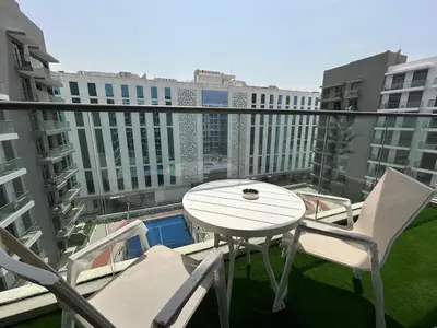 a white table and chairs on a balcony with buildings at Stylish 1-Bed Apartment in Laya Heights, Dubai in Dubai