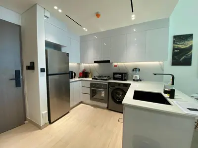 a kitchen with white cabinets and a stainless steel refrigerator at 1-Bedroom in Binghatti Emerald 1 with free Pool and Gym in Dubai