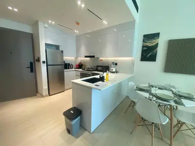 a kitchen with a sink and a table and chairs at 1-Bedroom in Binghatti Emerald 1 with free Pool and Gym in Dubai