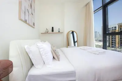 a white bed in a room with a window at Chic Riviera 27 - 1BHK - Pool , Gym , Parking in Dubai