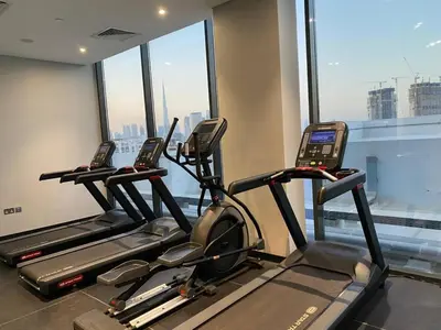 a gym with three tread machines in front of a window at Modern Studio in Azizi Riviera 10, Near Downtown in Dubai