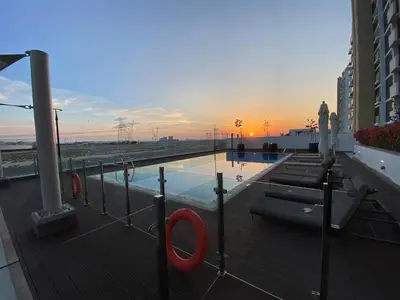 a pool on a building with a sunset in the background at Modern Studio in Azizi Riviera 10, Near Downtown in Dubai