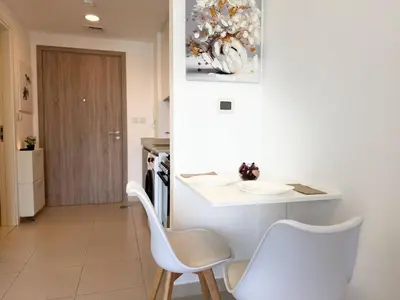a kitchen with a table and two white chairs at ASHRI HH | Elegant Studio | UNA Townsquare in Dubai