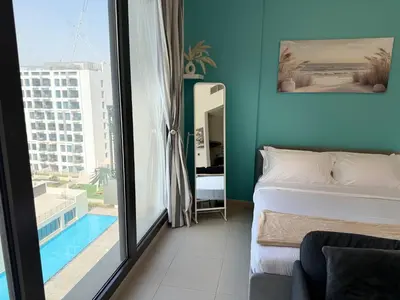 a bedroom with a bed and a view of a pool at ASHRI HH | Elegant Studio | UNA Townsquare in Dubai