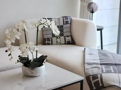 a white couch with a vase of flowers on a table at SOLARTE Luxe - NEW Canal Front Residence - Pool with Burj Views in Dubai