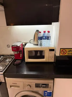a kitchen counter with a microwave and bottles of water at Stylish Studio in Business Bay Walking to Canal and Downtown in Dubai