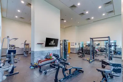 a gym with several treadmills and cardio machines at Burj Views Tower, 1 Bdr Apartment with Opera View in Dubai