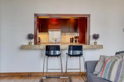 a kitchen with two bar stools in a living room at Burj Views Tower, 1 Bdr Apartment with Opera View in Dubai