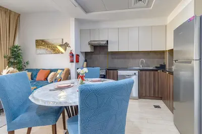 a kitchen and living room with a table and blue chairs at Remraam, 1 Bedroom in Al Ramth 11 - Allsopp & Allsopp in Dubai