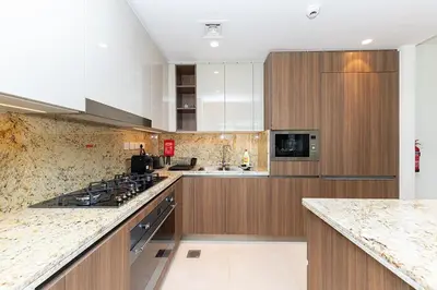 a large kitchen with wooden cabinets and a stove at Luxury 3BR Imperial Avenue Burj Khalifa Views in Dubai