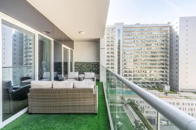 a balcony with a couch and chairs in a building at RH - Burj Khalifa view with large balcony, 02BR retreat in business bay in Dubai