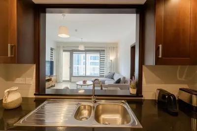 a kitchen with a sink and a living room at Vacay Lettings 1 bed with burj Khalifa View in Dubai